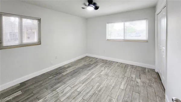 an empty room with wooden floor and windows