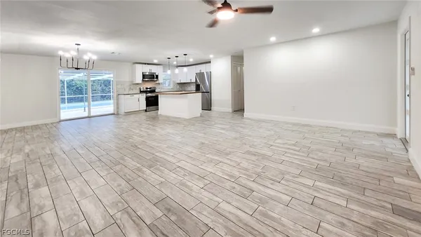 a view of a electric appliances in kitchen and empty room with wooden floor