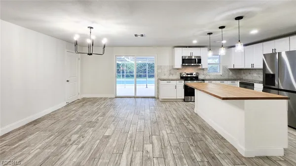 a large kitchen with granite countertop a large counter top space a sink stainless steel appliances and cabinets