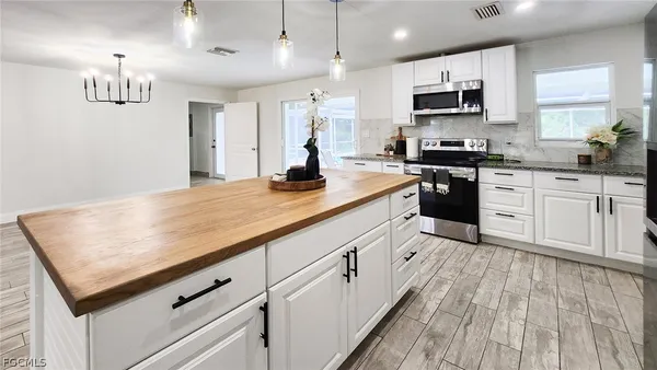 a kitchen with kitchen island granite countertop stainless steel appliances cabinets a sink and a wooden floor