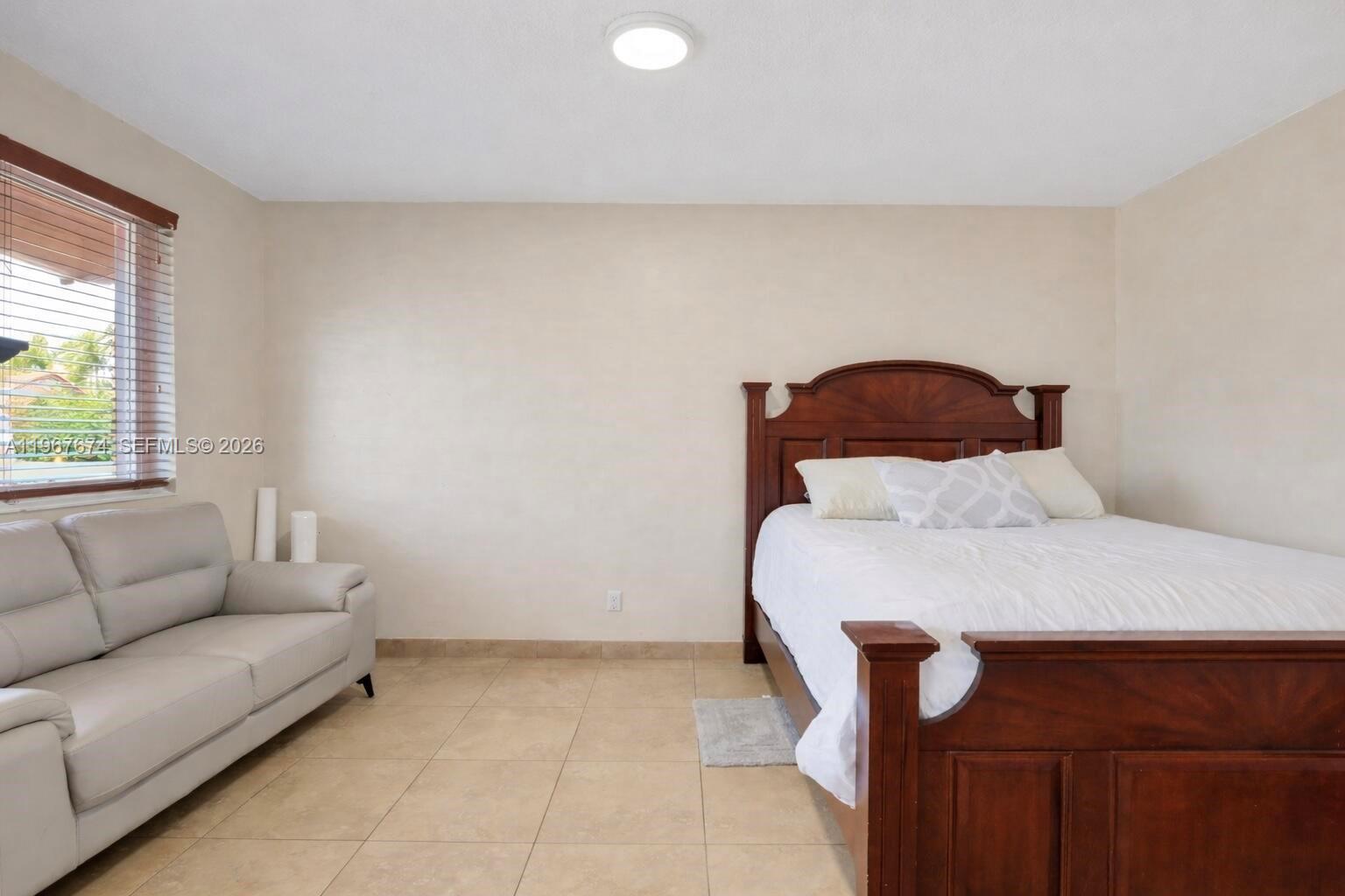 1901 Southwest 90th Avenue Miami, FL 33165 - Photo 13 of 25 a bedroom with a bed and a couch with exposed radiator