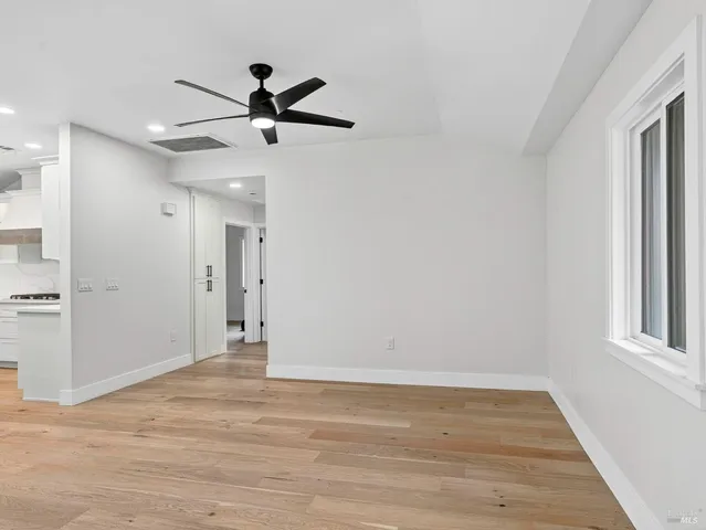 a view of empty room with wooden floor and fan