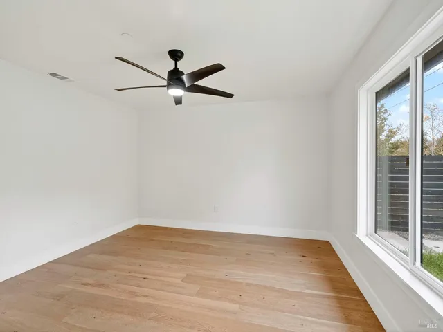 a kitchen with stainless steel appliances kitchen island granite countertop a stove a sink and white cabinets with wooden floor