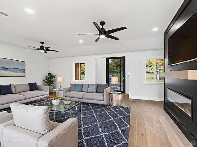a view of an empty room with wooden floor and a fireplace