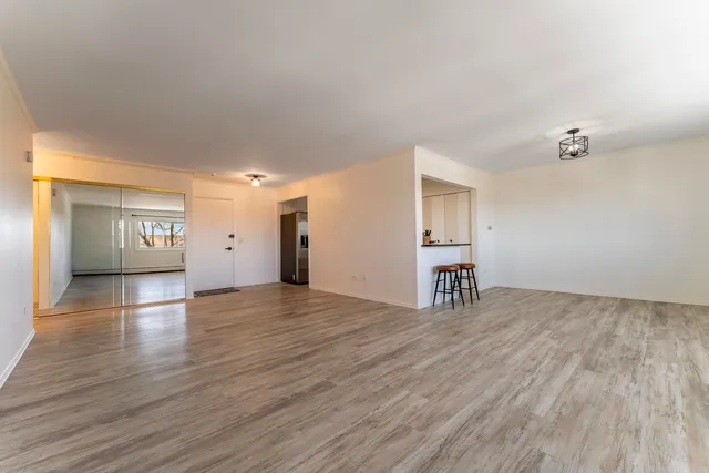 a view of an empty room with window and wooden floor