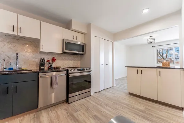 a kitchen with granite countertop white cabinets and stainless steel appliances