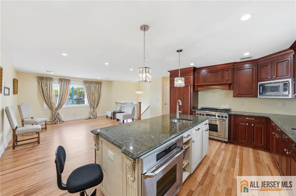 1084 Stelton Road Piscataway, NJ 08854 - Photo 4 of 20 a kitchen with stainless steel appliances granite countertop a stove top oven a sink dishwasher a dining table and chairs with wooden floor