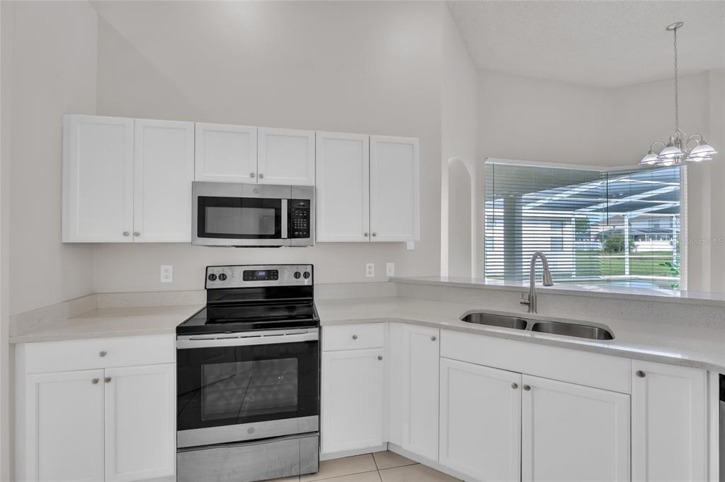 1047 Durango Loop Street Davenport, FL 33897 - Photo 6 of 35 a kitchen with white cabinets and a stove top oven