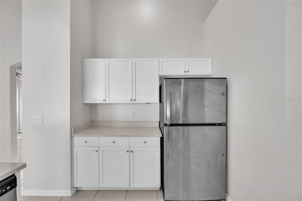 1047 Durango Loop Street Davenport, FL 33897 - Photo 7 of 35 a kitchen with a refrigerator and cabinets