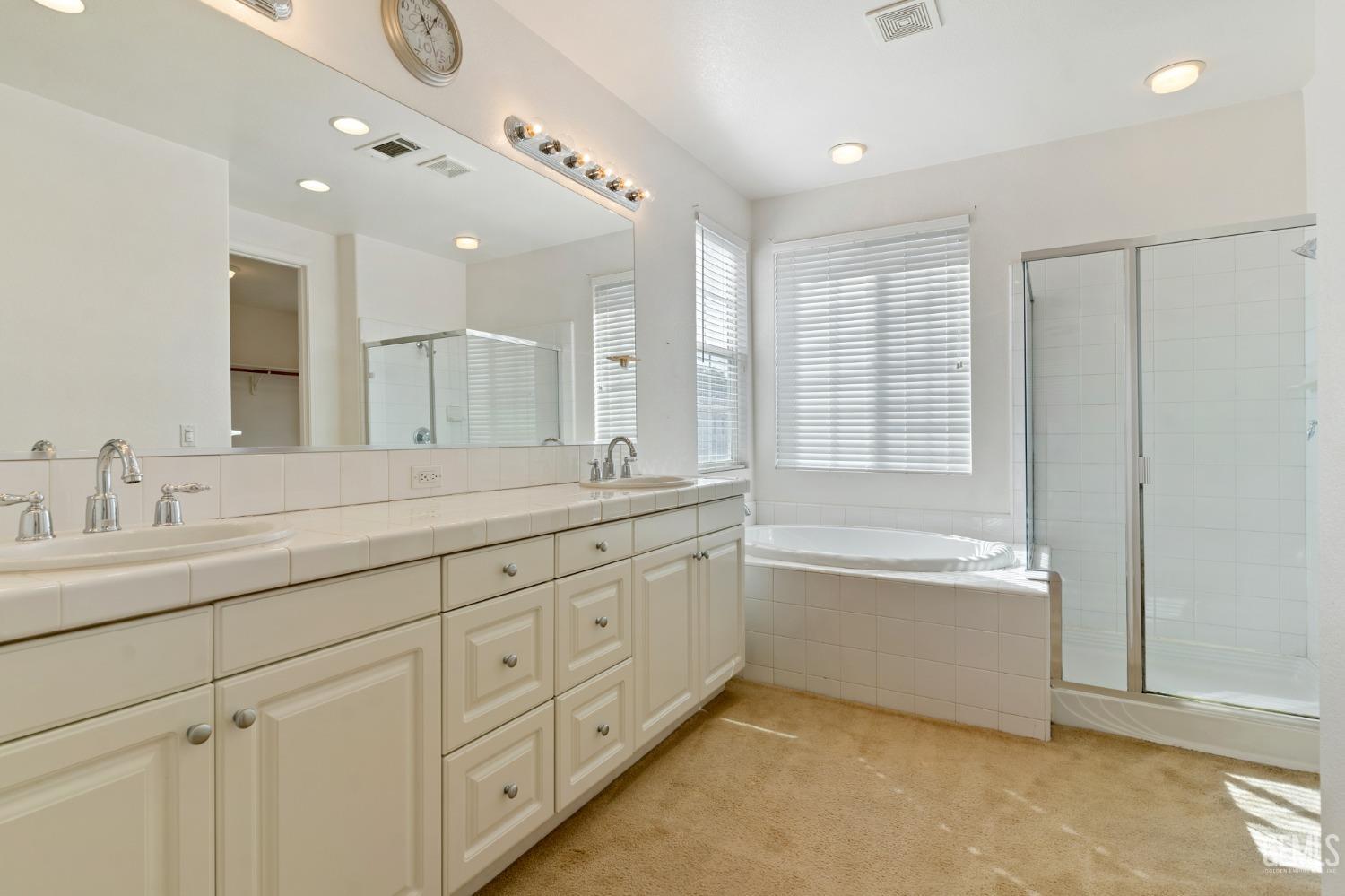 Undisclosed Address Bakersfield, CA 93306 - Photo 26 of 30 a spacious bathroom with a double vanity sink a mirror and a bathtub