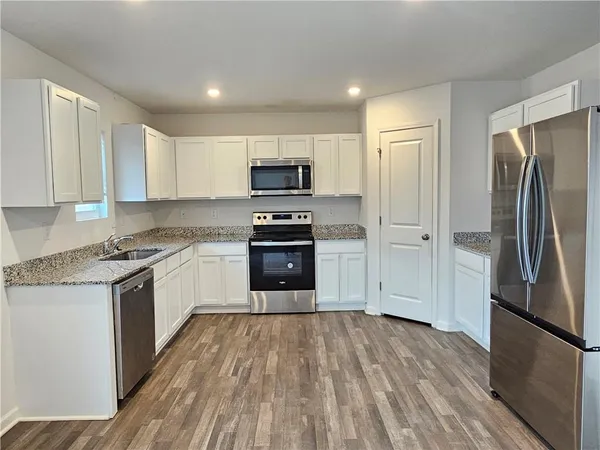a kitchen with granite countertop a refrigerator and a stove top oven