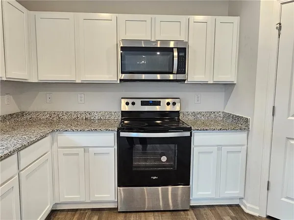 a kitchen with stainless steel appliances granite countertop white cabinets and a stove