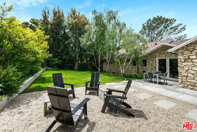 a view of pool with lawn chairs and large trees