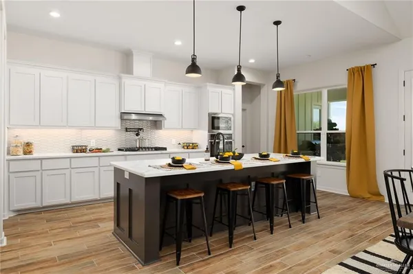 a kitchen with stainless steel appliances granite countertop a stove a sink dishwasher a refrigerator and white cabinets with wooden floor