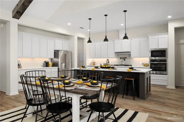 a kitchen with stainless steel appliances granite countertop a stove a refrigerator a kitchen island a table and chairs
