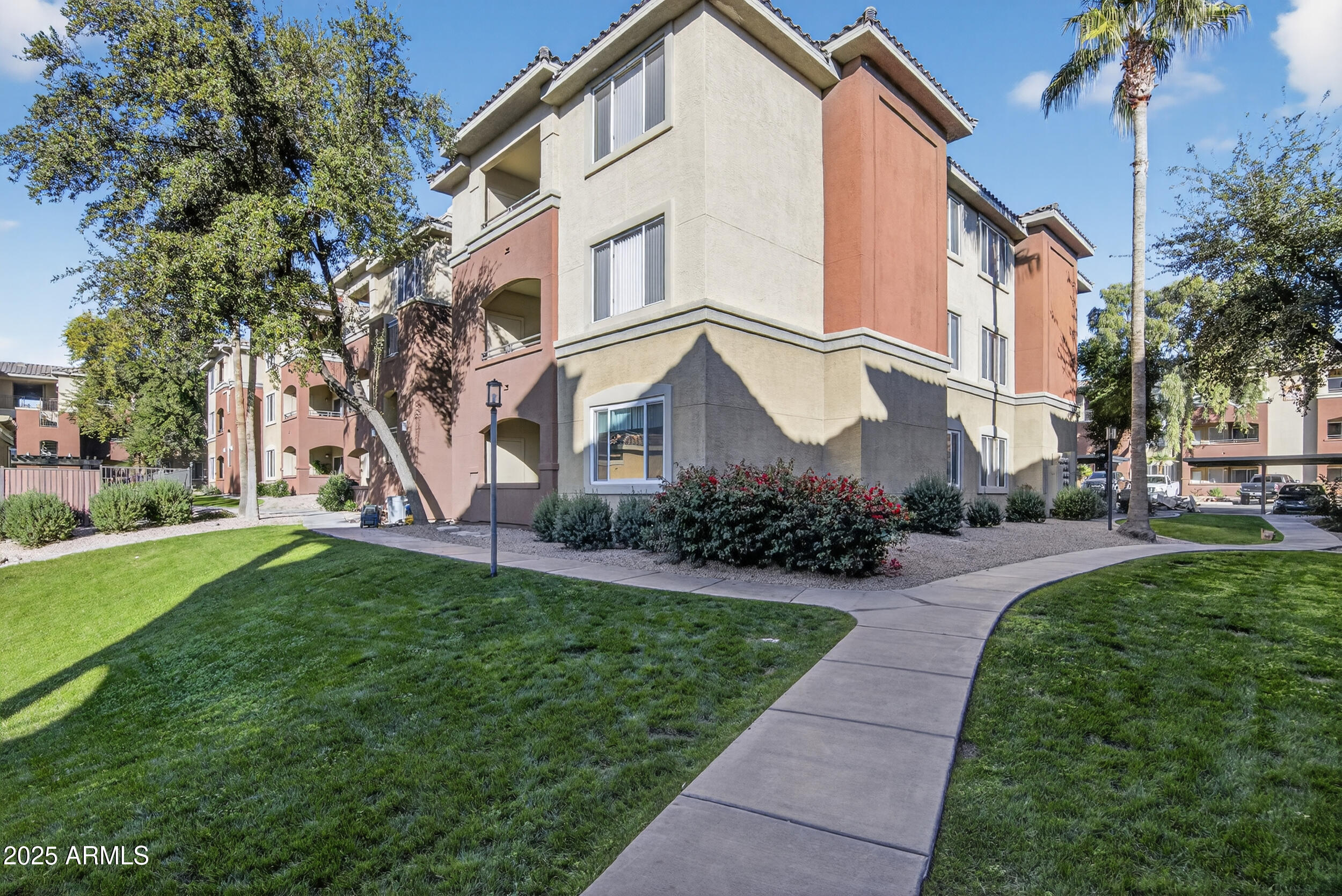 5401 East Van Buren Street, Unit 2076 Phoenix, AZ 85008 - Photo 2 of 41 a view of a white house next to a yard with big trees