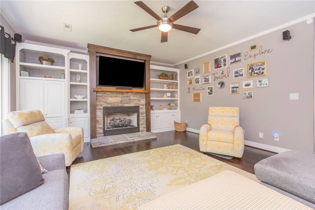 4420 Denver Cove Road Anderson, SC 29625 - Photo 16 of 50 This inviting living area features a stone fireplace, built-in shelving, and dark hardwood floors.