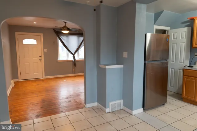 a view of a refrigerator in kitchen and an empty room in wooden floor