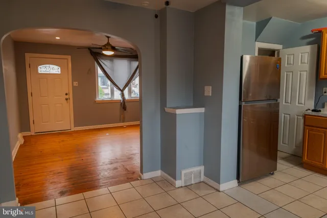 a view of a refrigerator in kitchen and an empty room in wooden floor
