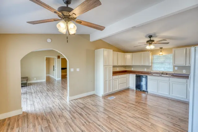 a open kitchen with a sink dishwasher a stove and a refrigerator with wooden floor