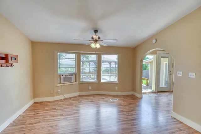 a view of an empty room with window and wooden floor