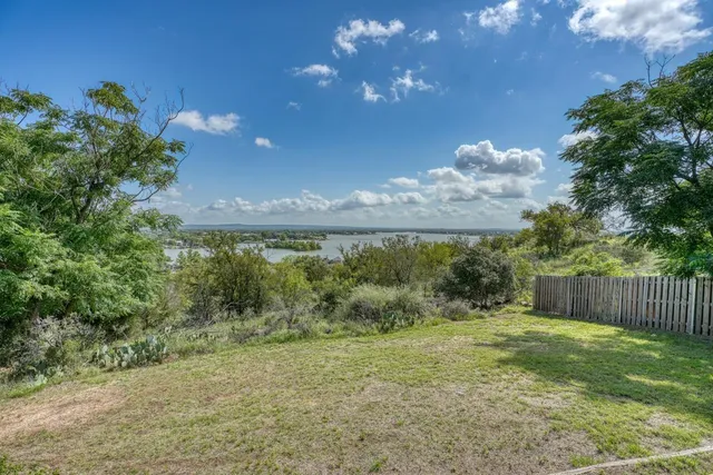 a view of a big yard with an tree and a fence