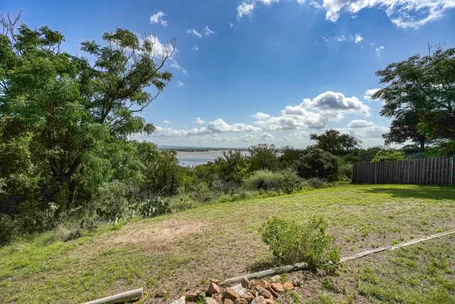 a view of a yard with flower plants and wooden fence