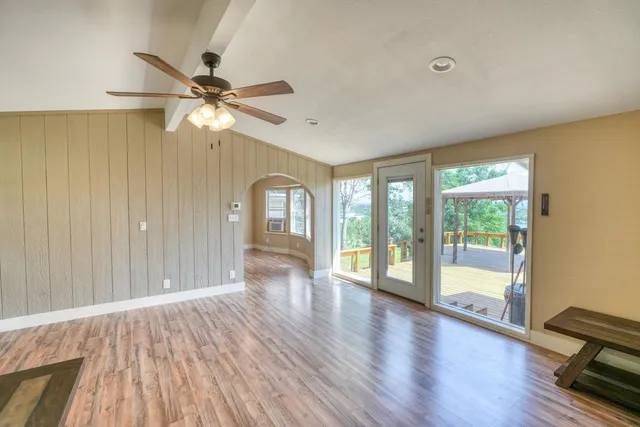 a view of an empty room with a window and wooden floor