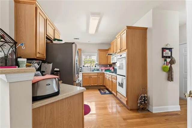 a kitchen with stainless steel appliances granite countertop a stove a sink dishwasher and white cabinets with wooden floor