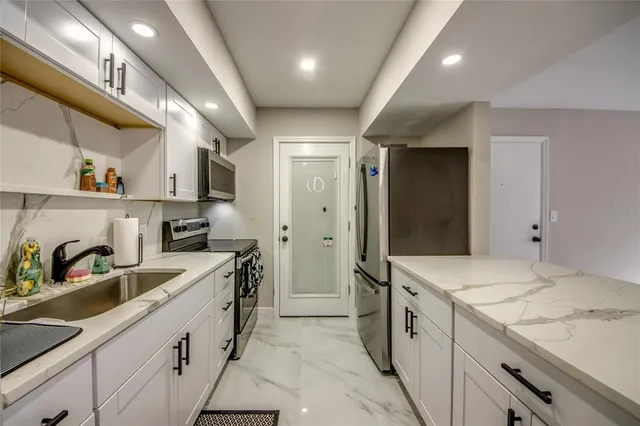 a large white kitchen with a sink and dishwasher a refrigerator with wooden cabinets