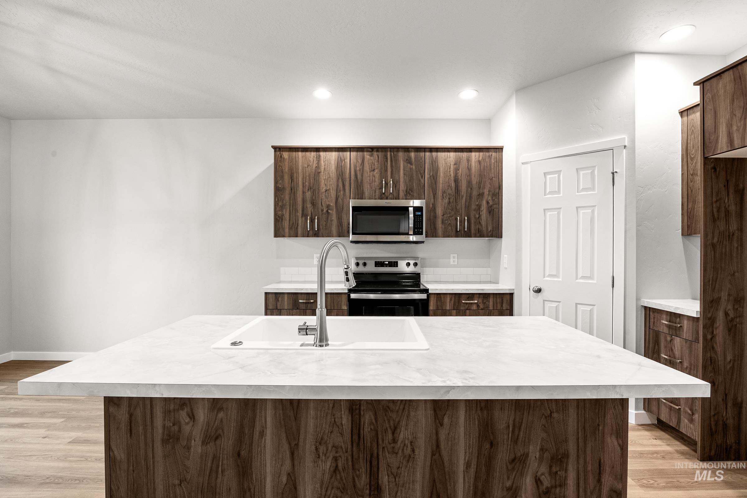 13656 Redway Court Caldwell, ID 83607 - Photo 5 of 21 Kitchen featuring stainless steel refrigerator, wood-finish cabinetry, white subway tile backsplash, and light-toned countertops