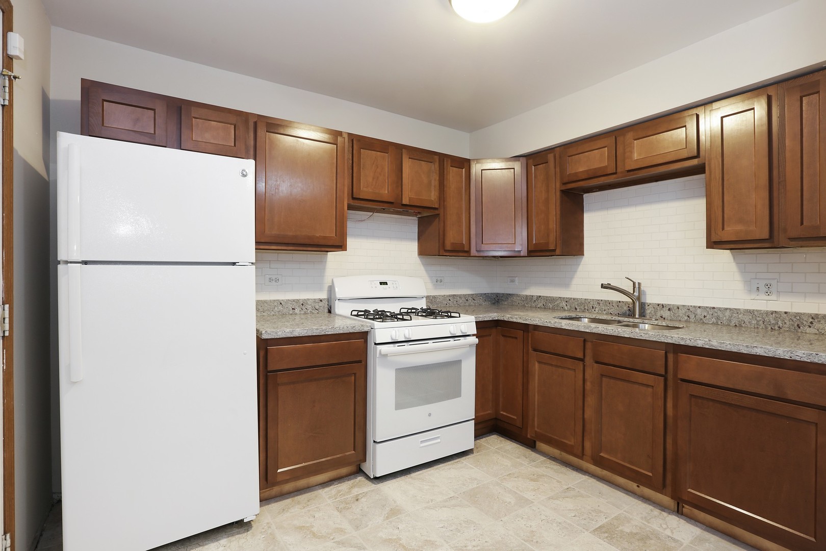 2414 West Harrison Street, Unit E Chicago, IL 60612 - Photo 7 of 15 a kitchen with a refrigerator sink and cabinets