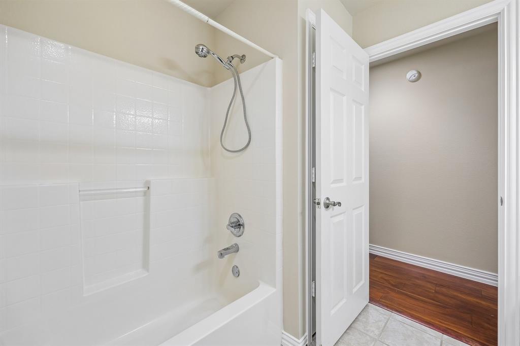 5409 Wedgefield Road Granbury, TX 76049 - Photo 19 of 39 Bathtub with a built-in shower niche, chrome fixtures, and a white tiled surround
