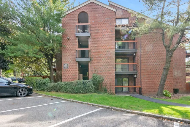 a view of a brick house with a yard and large trees