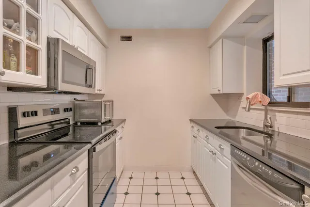 a kitchen with granite countertop a sink stove and cabinets