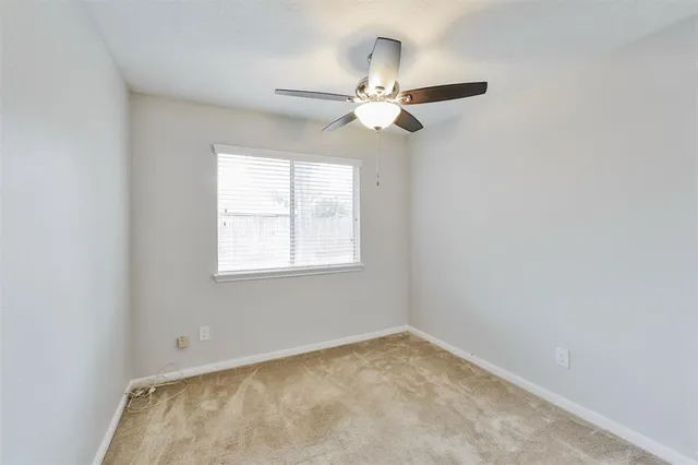 an empty room with a window and a fan