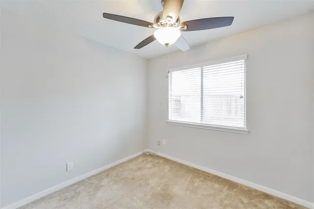 an empty room with a window and a fan