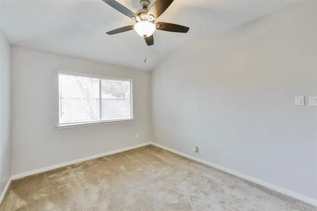 an empty room with a window and a fan