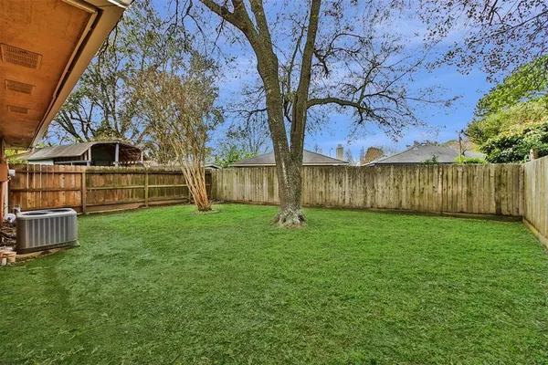 a view of a backyard with wooden fence and large trees