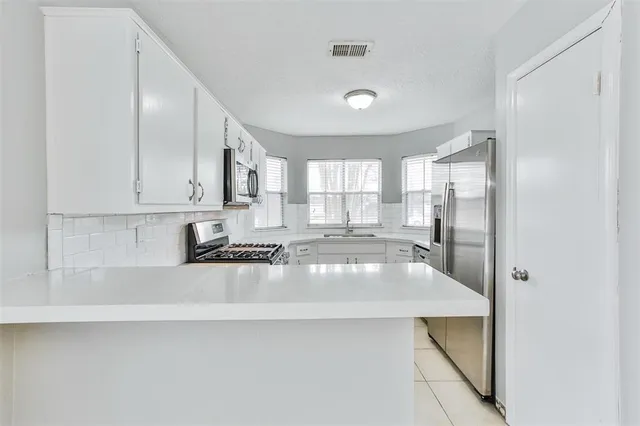 a large kitchen with stainless steel appliances a large counter top a stove and a refrigerator