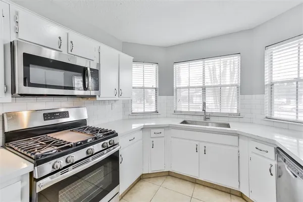 a kitchen with cabinets appliances a sink and a window