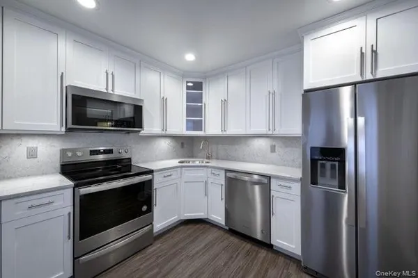 a kitchen with cabinets stainless steel appliances and wooden floor