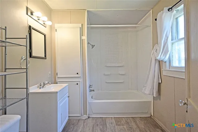 a bathroom with a tub shower vanity and a sink