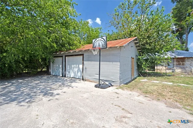 a backyard of a house with large trees and outdoor seating