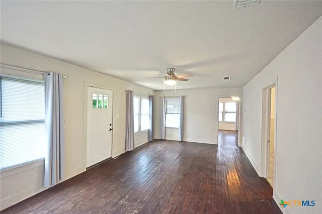 a view of an empty room with wooden floor and a window