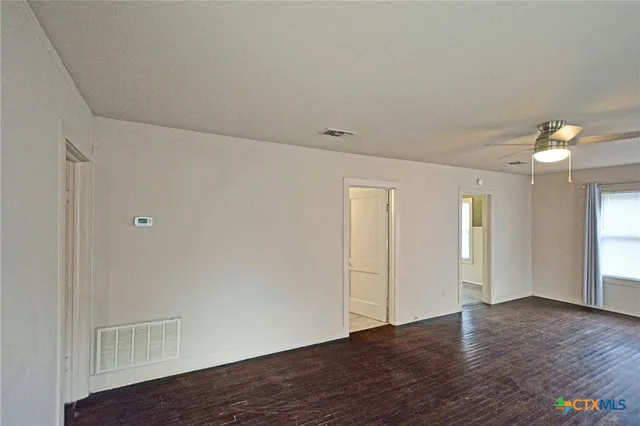 a view of an empty room with window and wooden floor
