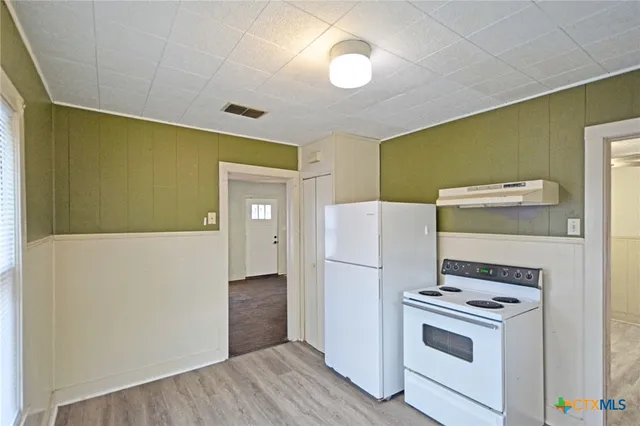 a kitchen with a refrigerator a stove and a wooden floor