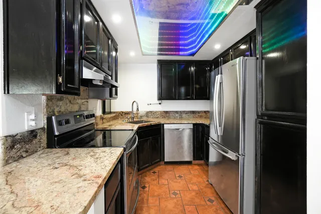 a kitchen with stainless steel appliances granite countertop a refrigerator a stove and a sink