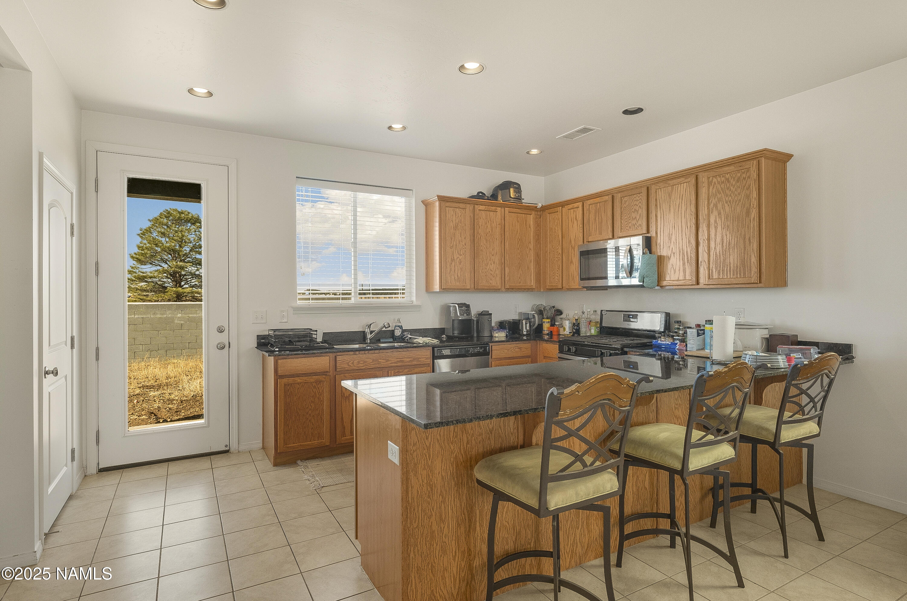 12361 Pegasus Road Bellemont, AZ 86015 - Photo 5 of 18 a kitchen with granite countertop a table chairs stove a sink dishwasher and cabinets