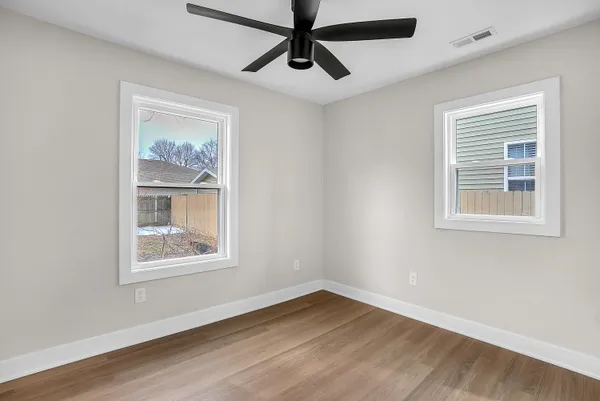 a view of an empty room with wooden floor and window